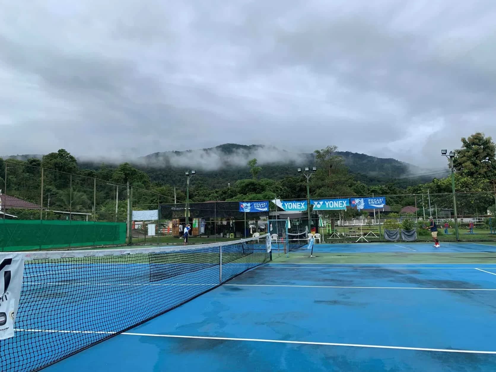 Outdoor tennis courts at Nut Tennis Academy in Mae Rim, Chiang Mai, with mountain backdrop